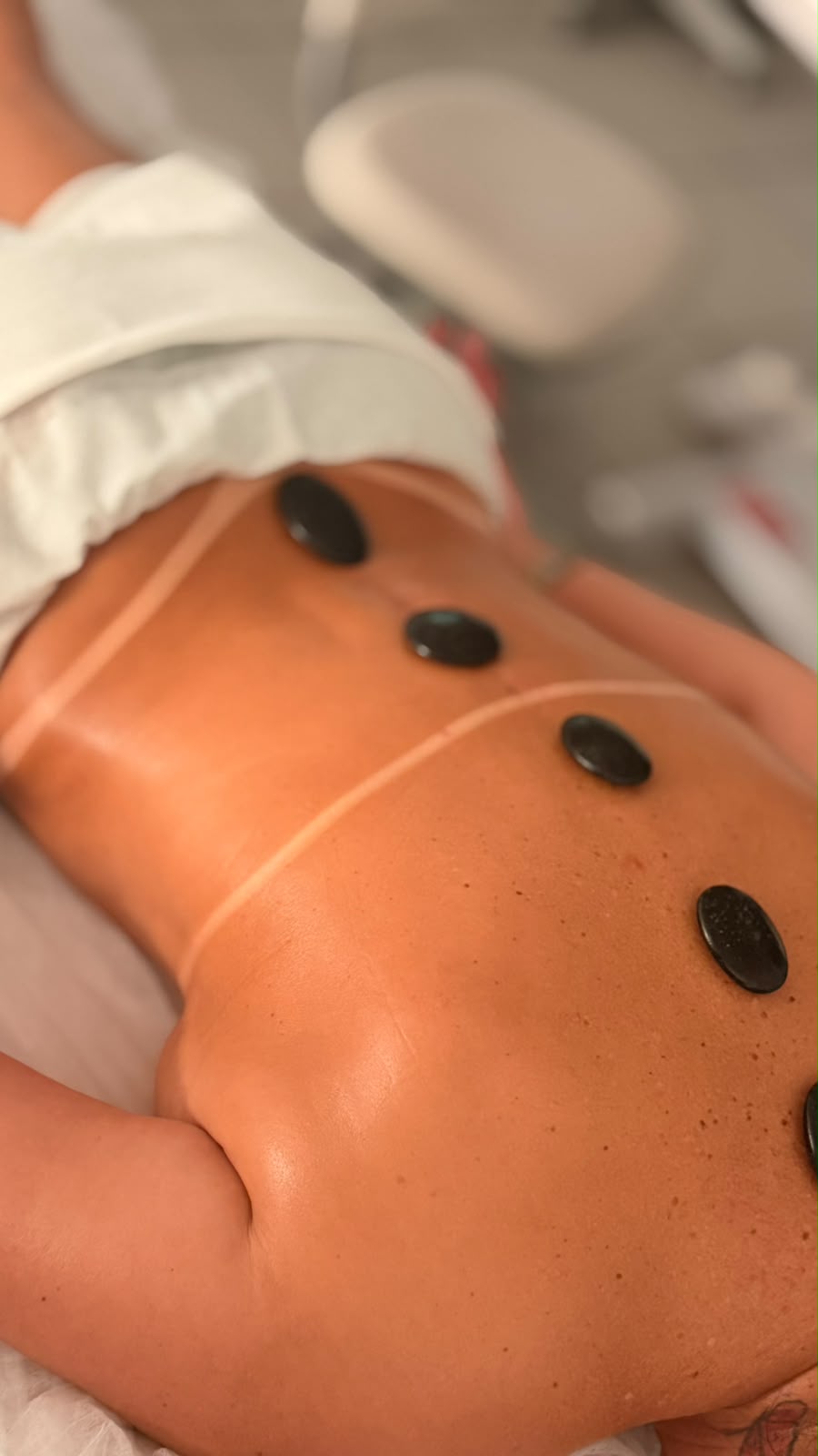 Massagem relaxante com pedras quentes sobre as costas bronzeadas.